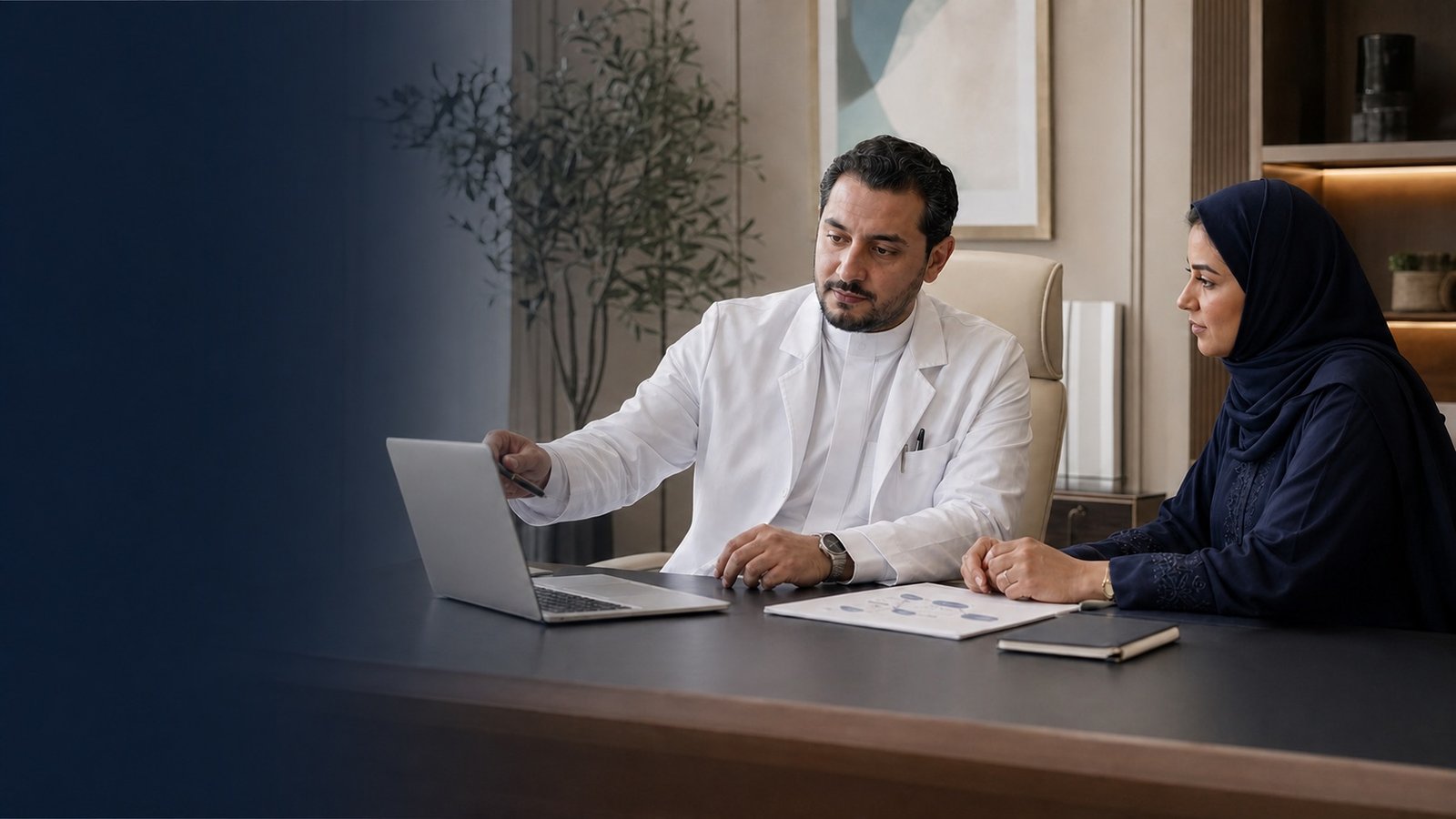A Saudi specialist physician and practice manager reviewing a digital patient journey in a clinic office